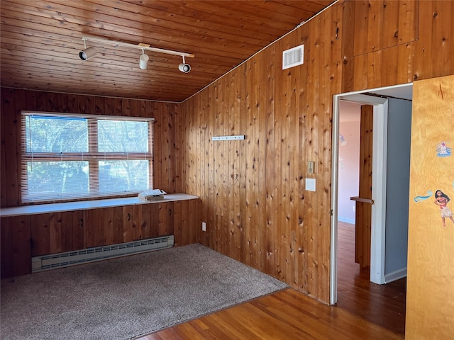 unfurnished room with wood-type flooring, a baseboard heating unit, and wood walls