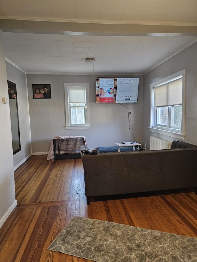 unfurnished living room with a wealth of natural light, hardwood / wood-style floors, crown molding, and radiator heating unit