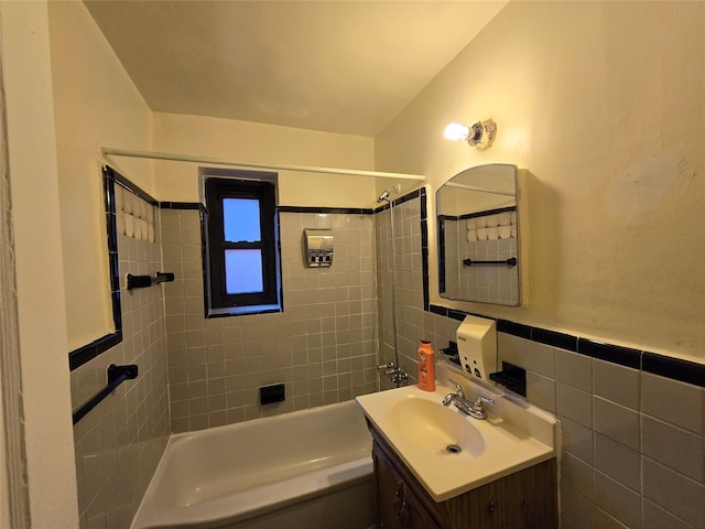 bathroom with tile walls, vanity, and tiled shower / bath combo