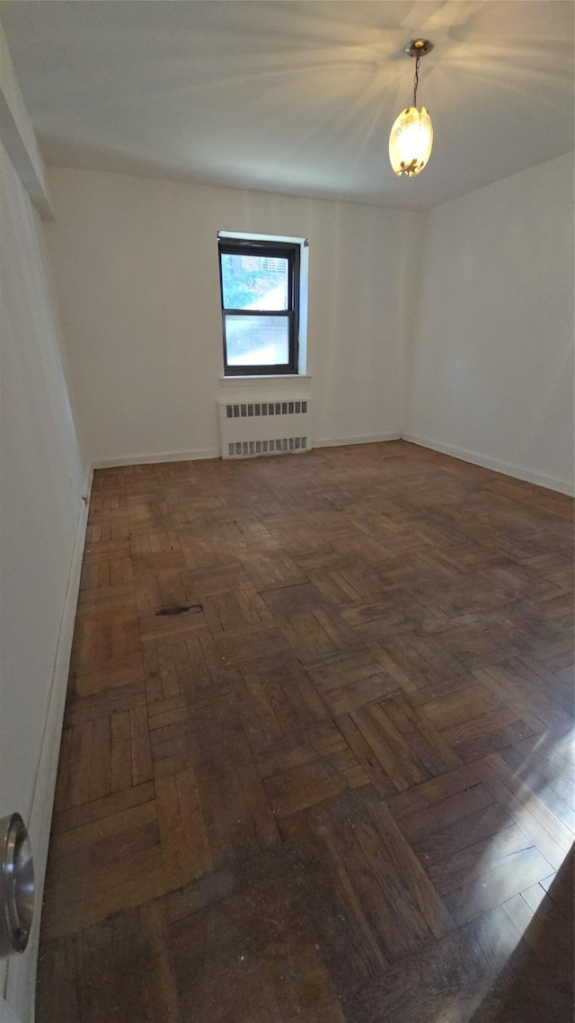 empty room featuring dark parquet flooring and radiator