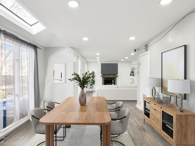 dining area with a skylight and light hardwood / wood-style floors