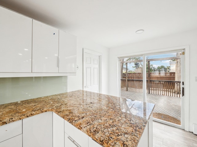 kitchen featuring stone countertops, light wood-type flooring, and white cabinets