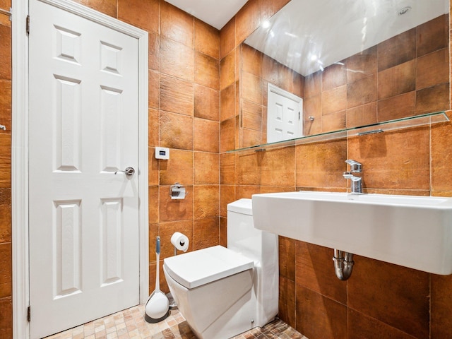 bathroom with toilet, sink, and tile walls