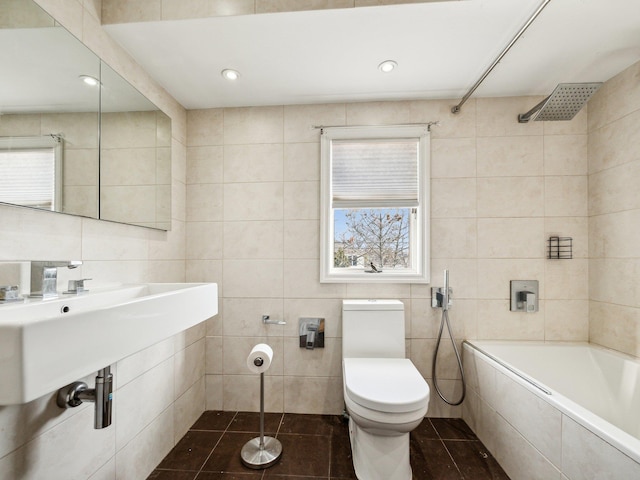 bathroom featuring toilet, tiled shower / bath combo, tile patterned flooring, and tile walls