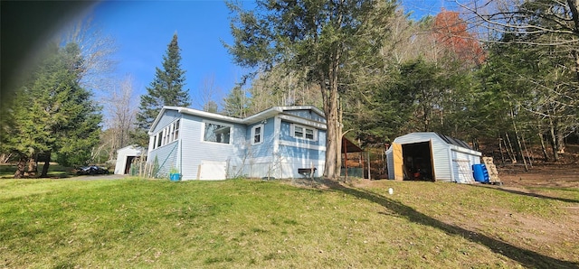 back of house with a storage unit and a lawn