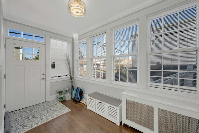 foyer entrance with radiator heating unit, crown molding, and dark wood-type flooring