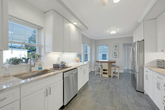 kitchen with sink, crown molding, white cabinetry, stainless steel appliances, and light stone countertops