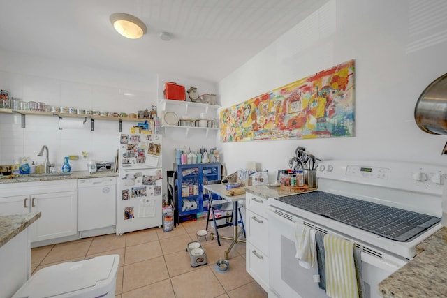 kitchen with sink, white appliances, light tile patterned floors, white cabinetry, and light stone countertops