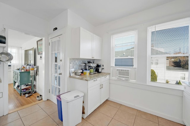 kitchen with tasteful backsplash, light stone counters, white cabinets, and light tile patterned flooring