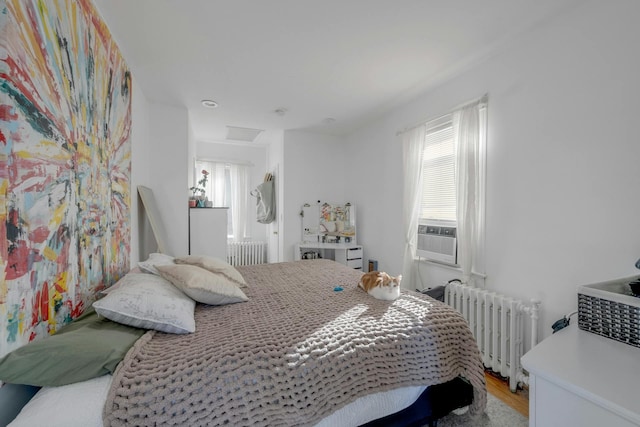 bedroom featuring wood-type flooring, radiator heating unit, and cooling unit