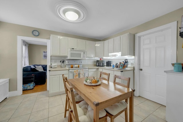 kitchen with white appliances, light tile patterned floors, and white cabinets