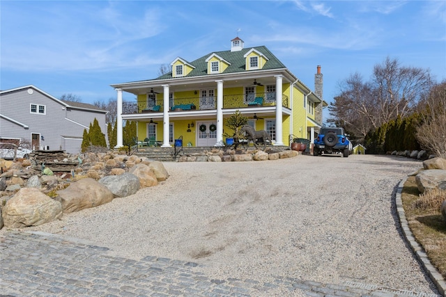 view of front of house featuring driveway, a porch, and a balcony