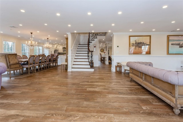 living room with light wood-type flooring, visible vents, crown molding, and stairs