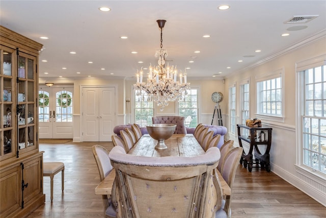 dining room featuring a wainscoted wall, visible vents, light wood-style floors, and ornamental molding