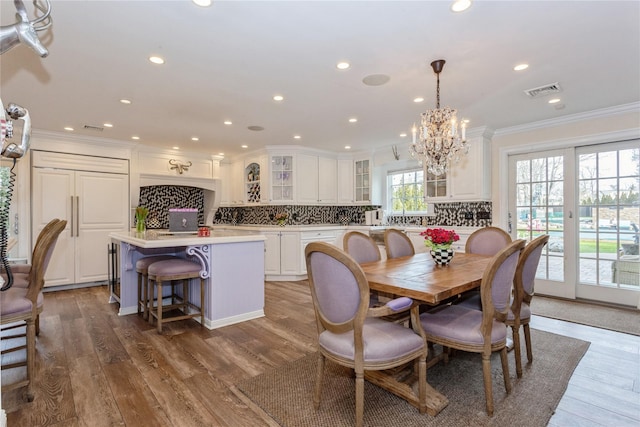 dining room featuring recessed lighting, wood finished floors, visible vents, ornamental molding, and an inviting chandelier