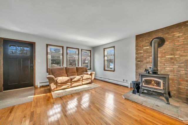 living room featuring a baseboard heating unit, a wood stove, and light hardwood / wood-style flooring