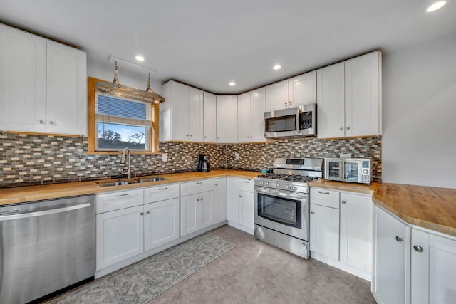 kitchen featuring butcher block counters, sink, stainless steel appliances, and white cabinets