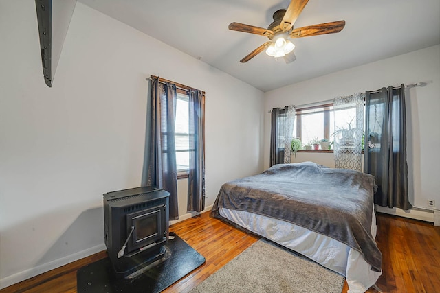 bedroom with lofted ceiling, dark hardwood / wood-style floors, ceiling fan, and a wood stove