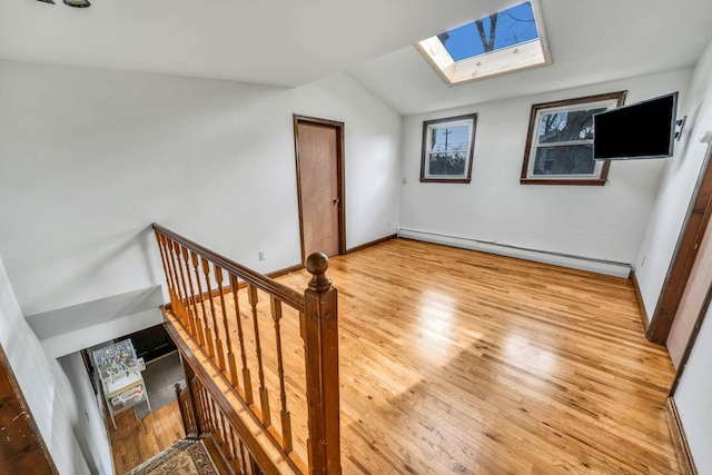 bonus room featuring light hardwood / wood-style flooring, lofted ceiling with skylight, and baseboard heating