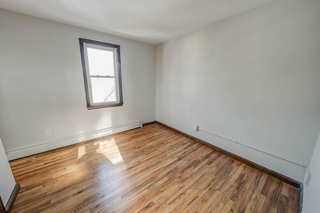 unfurnished room with a baseboard heating unit and light hardwood / wood-style floors