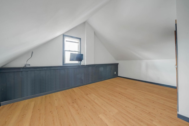 additional living space featuring vaulted ceiling and light hardwood / wood-style flooring