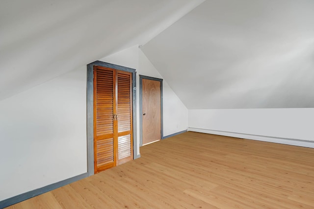 bonus room featuring lofted ceiling, a baseboard heating unit, and light hardwood / wood-style floors