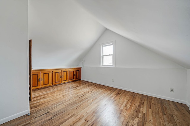 additional living space with vaulted ceiling and light hardwood / wood-style floors