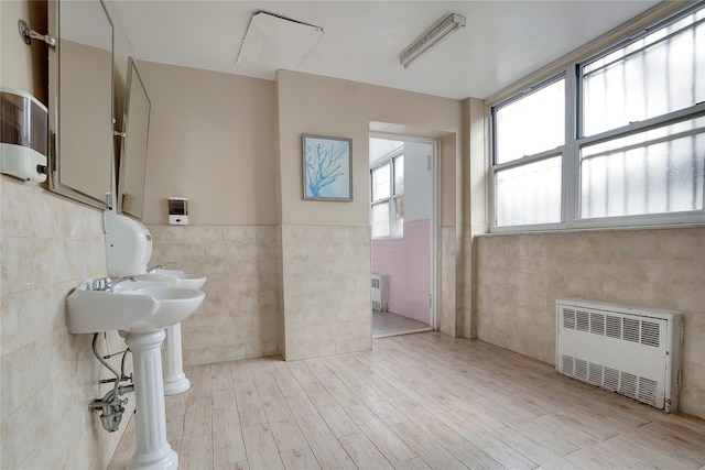 bathroom with radiator, hardwood / wood-style floors, and tile walls