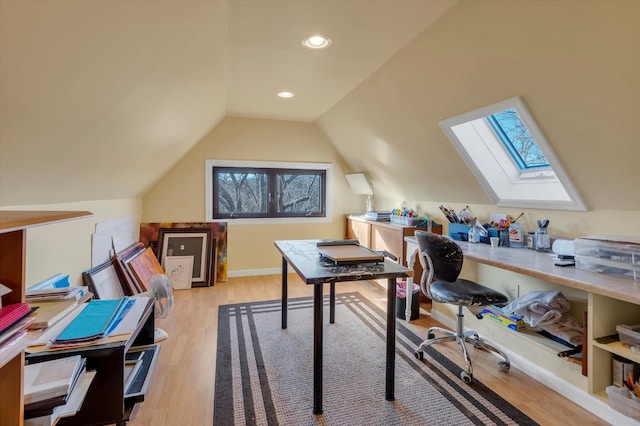 office space with lofted ceiling with skylight and light hardwood / wood-style flooring