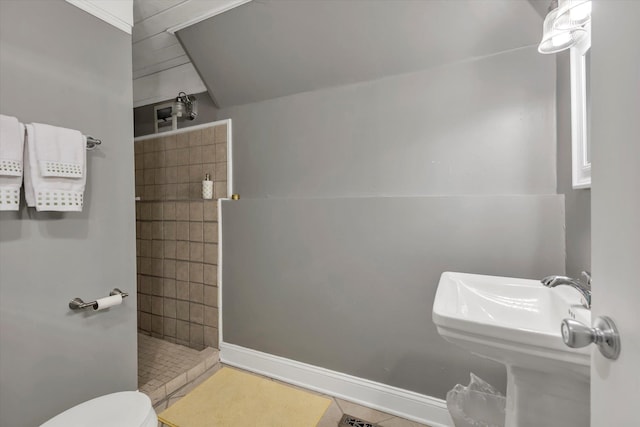 bathroom featuring tile patterned flooring, tiled shower, and toilet