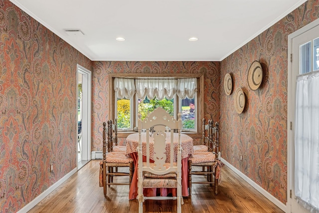 dining room featuring baseboards, a baseboard radiator, wood finished floors, and wallpapered walls