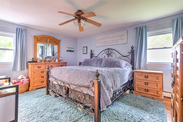 39 Cornwallis Rd, East Setauket, NY 11733 - bedroom featuring baseboard heating, multiple windows, ceiling fan, and light wood-style floors
