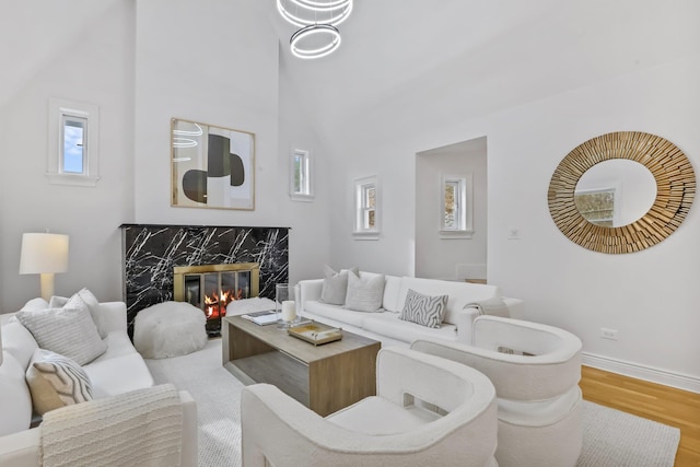 living room with a high ceiling, a fireplace, wood finished floors, and baseboards