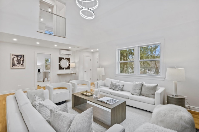 living area featuring baseboards, wood finished floors, a high ceiling, a wall mounted AC, and recessed lighting