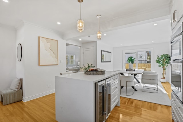 kitchen featuring beverage cooler, light countertops, baseboards, and light wood finished floors