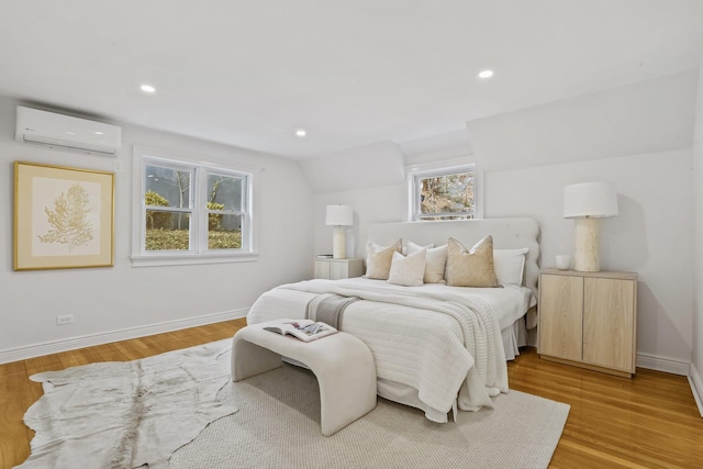 bedroom with light wood finished floors, recessed lighting, baseboards, and a wall mounted AC