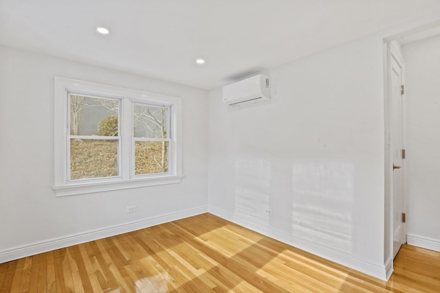 empty room with recessed lighting, light wood-style flooring, baseboards, and a wall mounted air conditioner