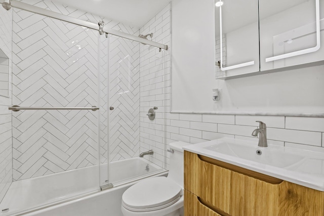 full bath with tasteful backsplash, toilet, shower / bath combination with glass door, vanity, and tile walls