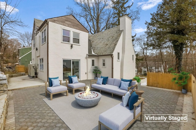 rear view of property with a patio area, a chimney, fence, and an outdoor living space with a fire pit