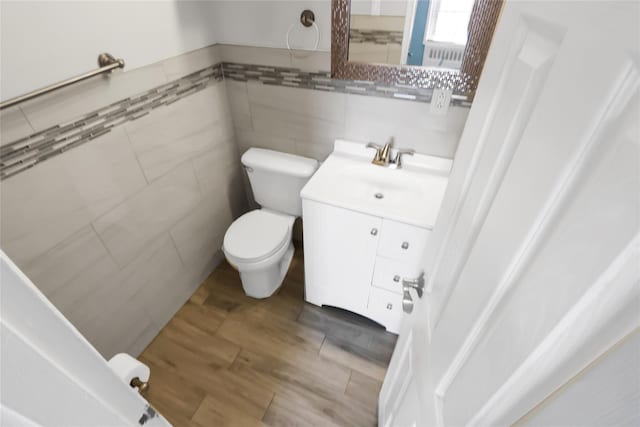 bathroom featuring wood finished floors, vanity, toilet, and tile walls