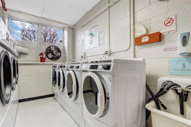 shared laundry area featuring concrete block wall and washing machine and clothes dryer