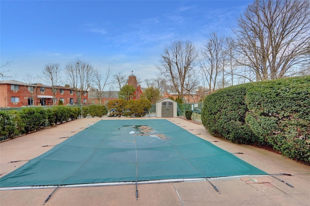 community pool featuring a storage shed, an outbuilding, and fence