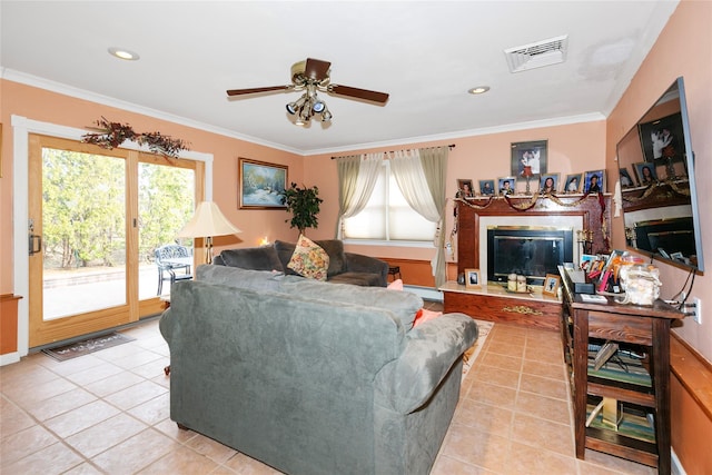 living area with a wealth of natural light, a glass covered fireplace, visible vents, and ornamental molding