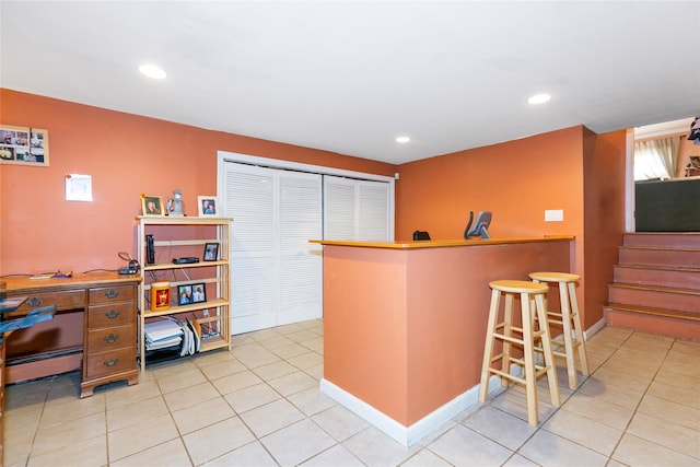 kitchen featuring light tile patterned floors, a baseboard radiator, a kitchen breakfast bar, and recessed lighting