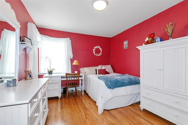 bedroom featuring an accent wall and light wood-type flooring