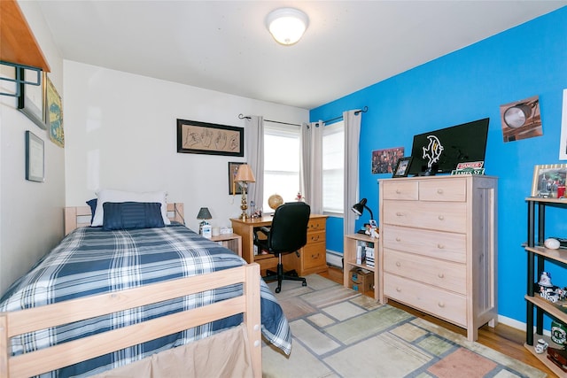 bedroom featuring a baseboard radiator, baseboards, and wood finished floors