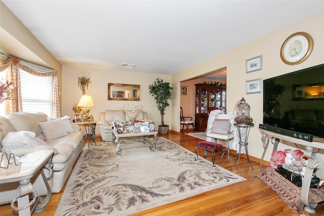 living area featuring wood finished floors, visible vents, and baseboards