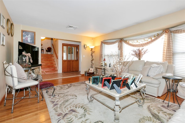 living area featuring stairs, visible vents, a wealth of natural light, and wood finished floors