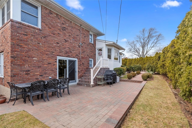 back of property featuring outdoor dining area, a patio, and brick siding