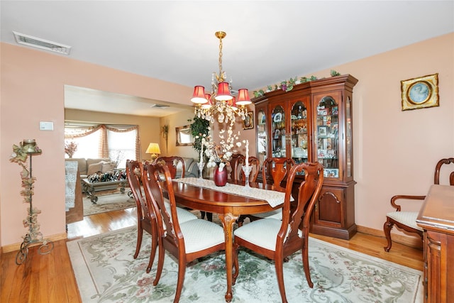 dining room featuring an inviting chandelier, baseboards, visible vents, and wood finished floors